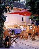 Mediterrane Tafel unter Rotem Stoffschirm im Innenhof, Abendstimmung