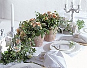 Üppiges Blumenarangement mit Rosen auf weiß gedecktem Tisch