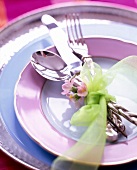Close-up of cutlery and ornamental quince branch tied with green ribbon on plate