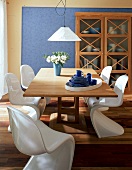Eßzimmer: fünf weiße Panton-Stühle, heller Tisch,Vitrinen-Schrank