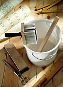 Bucket, brush tassel and wallpaper on wooden floor