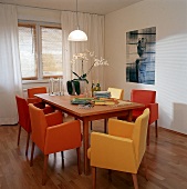 Orangefarb. + gelbe Sessel stehen um den großen Tisch