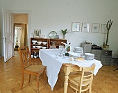 Ein alter Bauerntisch mit weißer Tischdecke und Geschirr(Weißbrot)