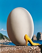 A yellow paint pump stands in front of a large white egg