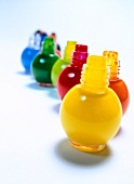 Multi-coloured open nail paint bottles on white background