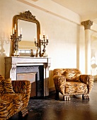 Zwei Leopardenfell-Sessel stehen vor dem Kamin (korinthische Säulen)