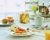 Frühstückstisch mit Lachsbrötchen, Muffins, Toast und Kaffee