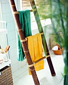 Yellow and green towel hanging on bamboo ladder in bathroom
