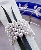 Ein Serviettenring aus Perlen und 2 Grashalme dekorieren eine Serviette