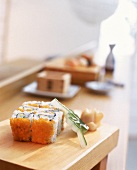 Sushi: 6 Stück California Uramaki liegen auf einem Holzbrett