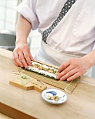 Step: Mit der Sushimatte werden Reis Lachs und Algenblatt aufgerollt