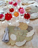 Tischset aus getrockneten Blättern, Dahlienblüten in Gläsern