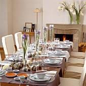 Asian table laid with crockery and tall vases with flowers