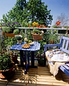 Balkon mit Holzdielen, rustikalen Gartenmöbeln u. Pflanzen