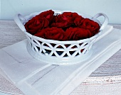 weiße Porzellanschale m. roten Rosen blüten.