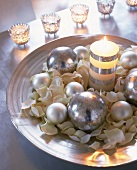 Silberschale gefüllt mit Blütenbett, Silberkugeln u. gestreifter Kerze