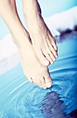 Close-up of feet being dipped in blue water