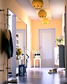 Yellow wall with large mirror, lamp, and perforated door in corridor