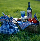 Blue wine bottle, tomatoes and gooseberries on blue tea towel