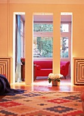 Blick durch einen Säulendurchgang auf rotes Sofa im Erker