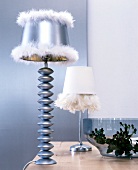 White and silver modern lampshades with feathers on table