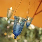 Hängende Windlichter aus blauem Glas mit brenenden Kerzen