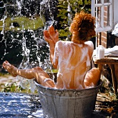 Frau badet sich außen mit pflegenden Zusätzen