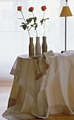 Stilvolle Decken in champagnerfarben drei Vasen mit einzelnen Rosen.