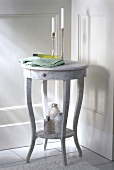 Small round marbled table with three various bath salts, candle stand and towels