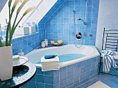 Eckbadewanne in blau gefliestem Bad unter der Dachschräge