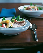 Red snapper in coconut sauce with pasta and sugar snap peas in white bowl