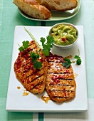 Turkey cutlets with coriander leaves and bowl of avocado sauce on plate