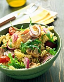 Pasta salad with tuna and arugula in green bowl