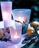 Lit candle in small glass on table in garden