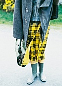 Frau trägt gelben Wickelrock mit Schottenkaro, Gummistiefel