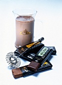Glass of grazer drinking chocolate with five chocolate bars and wire whisk