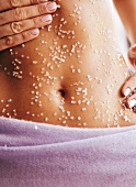 Close-up of woman rubbing sea salt on her belly