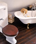 Freistehende Wanne und Toilette mit Spülkasten und Holzsitz