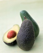 Zwei Avocados, im Hintergrund eine halbierte unscharf