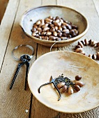 Bastelmaterial auf einem Tisch: Nüsse, Maronen, Perlen und Draht