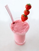 Low-fat cocktail of strawberry shake with three strawberries on stick