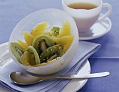 Kiwi-Orangenobstsalat mit gehackten Mandeln, in weißer Schale angerichte