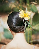 Frau hat ihr brünettes Haar mit einer gelben Blume festgesteckt
