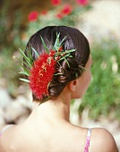Frau hat ihr Haar hochgesteckt und mit einer roten Blüte festgesteckt