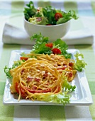 Ham pasta with pepper, green salad and cherry tomatoes on plate