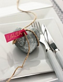 Close-up of heart shaped stone and name card tied with coarse rope on plate