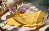 Menükarte aus gelbem Büttenpapier,in dem zarte Hortensienblüten stecken