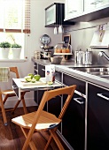 Space saving kitchen with drawer pull out table and wooden folding chairs