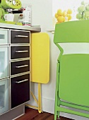 Platzsparen in Küche: Klappstuhl und - Tisch in gelb und grün verstaut