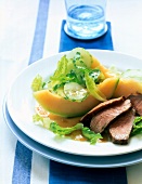 Close-up of salad with melon and duck breast on plate